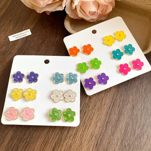 Dettaglio del set di 12 orecchini a perno a fiori in smalto colorato su schede bianche