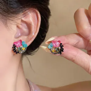 Macro detail of colorful dopamine butterfly floral earrings with sparkling rhinestones