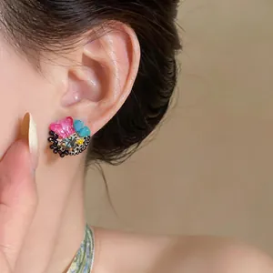 Close-up detail of colorful dopamine-style flower stud earring with gems worn on ear