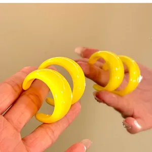 Primo piano dettagliato di orecchini a cerchio a C in resina giallo brillante