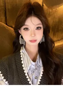 Model wearing elegant silver geometric tassel earrings in a warm lighting view.