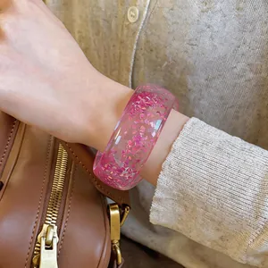 Detailed macro view of a pink transparent resin bangle with shiny inclusions
