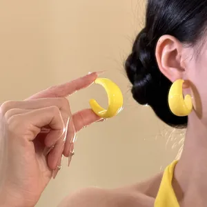 Orecchini a perno a forma di C in resina gialla spessa su modella color caramella