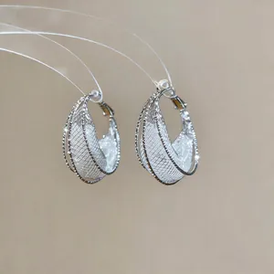 Detail shot of silver mesh hollow crescent earrings with sparkling crystal accents.
