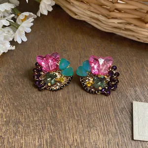 Close-up of colorful butterfly crystal stud earrings with floral and bead details.