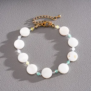Close-up of elegant gold bracelet with circular white shell beads and colored glass accents