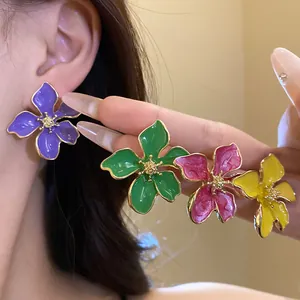 Detail of vibrant flower enamel stud earrings with silver needles on a model's ear