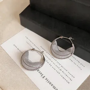 Detailed view of silver-colored hollow mesh crescent moon hoop earrings for women.
