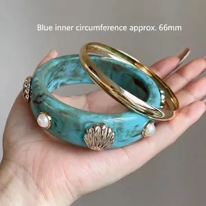 Dettaglio del bracciale in resina marmorizzata blu con borchie a conchiglia