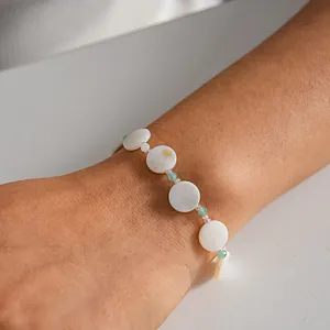 Detailed macro view of a beaded bracelet with white shell circles and green accents.