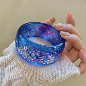 Macro detail of blue resin bangle with iridescent sparkling flakes and smooth finish