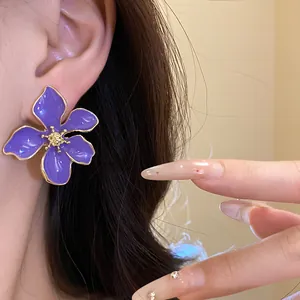 Detailed macro view of an elegant purple oil-drop flower stud earring worn on ear