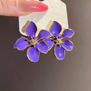 Close-up of elegant purple flower enamel stud earrings with golden center.