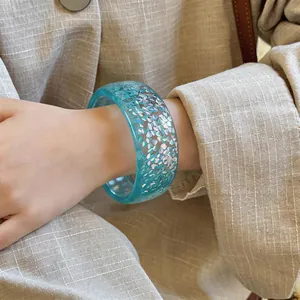 Detailed macro view of a light blue translucent resin bangle with iridescent flakes