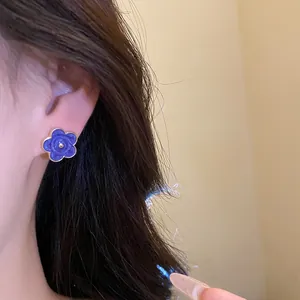 Primo piano di orecchino a fiore viola con bordo dorato su una modella elegante