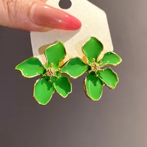 Close-up of green dripping oil flower earrings with gold-toned edges and stamen detail