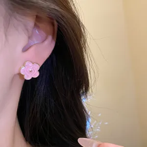 Primo piano di un dolce orecchino a lobo a forma di fiore in smalto rosa all'orecchio