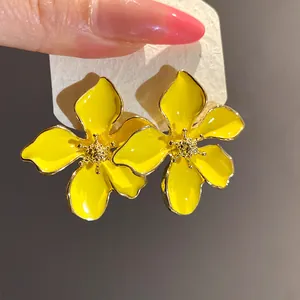 Close-up of bright yellow enamel flower stud earrings with elegant gold trim details