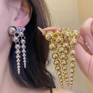 Close-up of vintage metallic bead cluster dangle earrings in gold and silver finish.