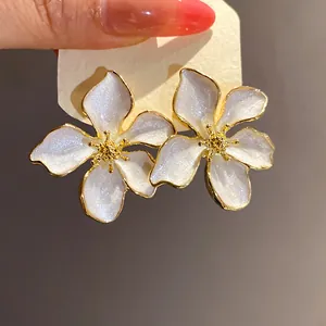 Detailed macro view of white pearlescent flower stud earrings with elegant gold edges.
