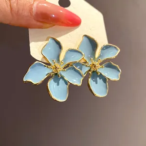 Detail shot of elegant blue flower enamel stud earrings with gold-tone edges