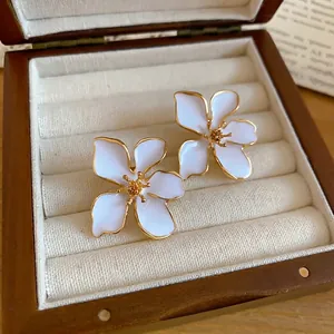 Elegant white enamel flower stud earrings with gold trim in a luxury wooden box