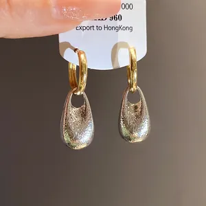 Macro view of vintage style two-tone earrings with textured silver waterdrop pendant