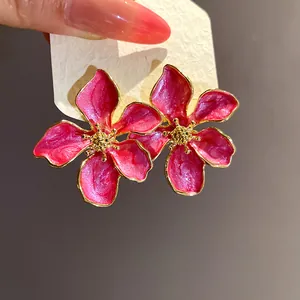 Detailed close-up of elegant pink oil-drop flower stud earrings with gold trim on a display card