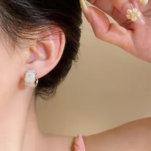 Close-up of French style zircon hoop earrings worn on ear, showing elegant textures.