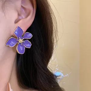 Close-up of elegant purple flower drip oil stud earring worn on the ear for women