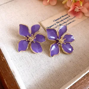 Macro detail view of elegant purple oil-dripped flower stud earrings with gold edges
