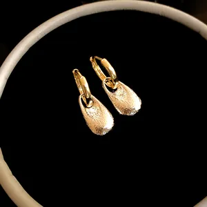 Close-up macro view showing the detailed texture of golden wrinkled drop earrings