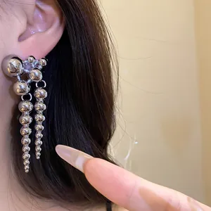 Detailed close-up of elegant silver beaded drop earrings with unique spherical clusters on a model