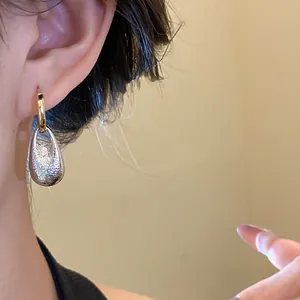 Close-up shot of a vintage pleated water drop pendant earring worn on a model's ear