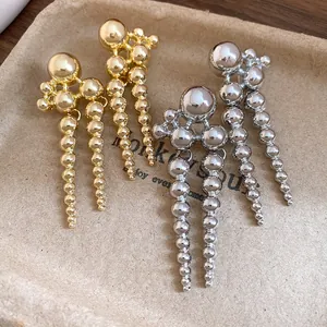 Close-up of gold and silver beaded tassel dangle earrings with a vintage finish.