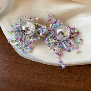 Macro view of vibrant sequin fringe and textured silver sphere stud earrings.