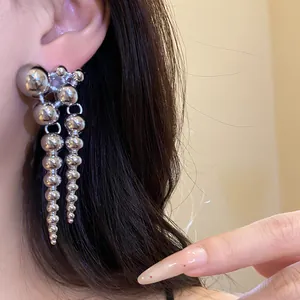 Close-up of minimalist silver dangling earrings featuring polished metal spheres