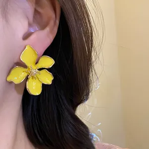 Vibrant yellow enamel flower stud earrings with silver needles for a fresh summer look.