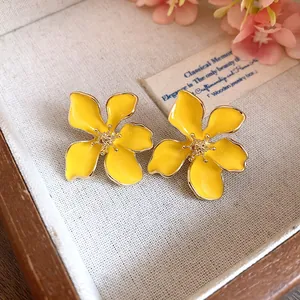 Close-up of elegant yellow enamel flower earrings with gold-tone edges and center