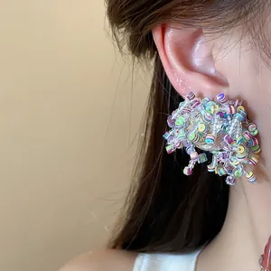 Close-up of a colorful sequin and bead stud earring on an ear, irregular design