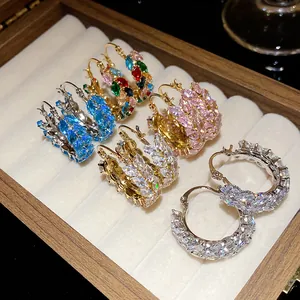 Close-up detail of colorful marquise-cut zircon hoop earrings in a wooden jewelry box
