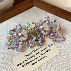 Detailed close-up of colorful beaded stud earrings with textured silver spheres