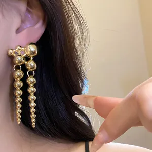 Close-up of elegant gold ball dangle earrings with a vintage minimalist aesthetic design
