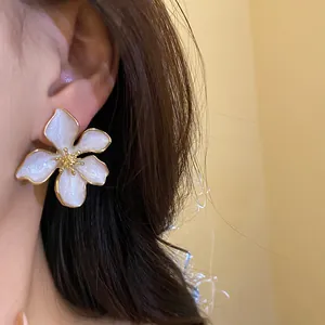 Elegant white enamel flower earrings with sparkling petals and gold-tone center detail