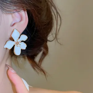 Close-up detail of an elegant white oil-drop flower stud earring with golden edges