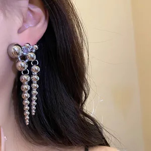 Detailed macro view of stylish silver beaded tassel drop earrings worn by an Asian model