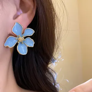 Detailed view of an elegant blue enamel flower earring with a gold-plated silver needle