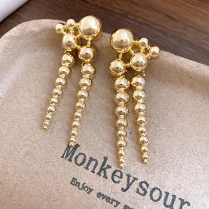 Macro view of vintage gold cascading bead earrings on a textured paper display tray