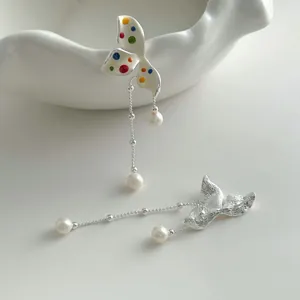 Close-up of silver flower earrings with colorful polka dots and elegant pearls