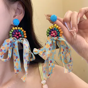 Vue détaillée de boucles d'oreilles bohèmes avec perles en bois et nœuds bleus